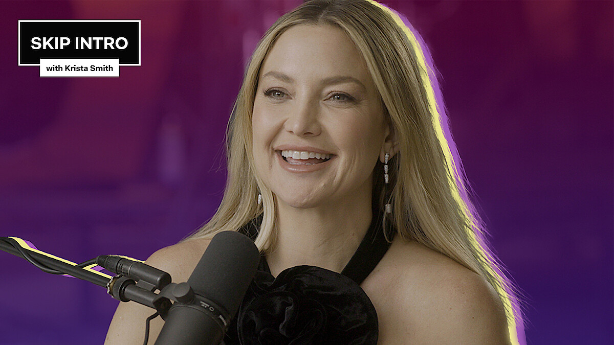 Kate Hudson is smiling as she sits in front of a microphone.