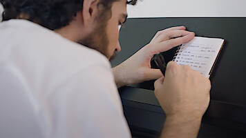 Cantor Jão anota versos para uma música numa folha de papel