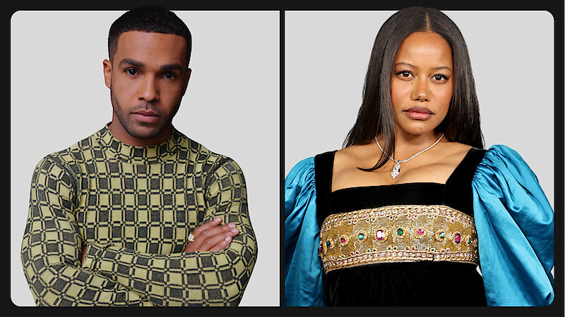 Two people posing against a plain gray background; the person on the left wears a patterned long-sleeve shirt, arms crossed, while the person on the right wears a dress with blue puffed sleeves and decorative details.