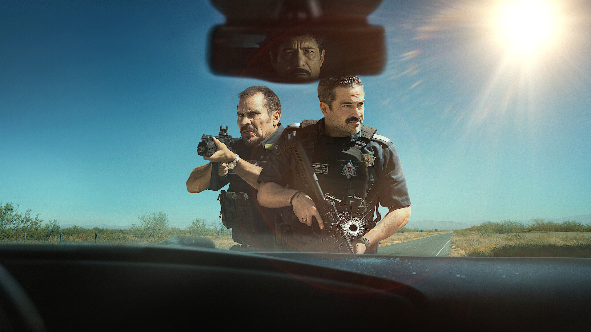 Two armed police officers stand in front of a car pointing their guns, with a bullet hole in the windshield, a rural deserted road and clear blue sky visible in the background, and a man’s reflection in the rearview mirror.