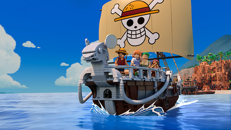 LEGO pirate ship with four minifigures sailing on blue water, featuring a sail with a skull and crossbones wearing a straw hat, under a clear blue sky with a coastline and mountains visible in the background.