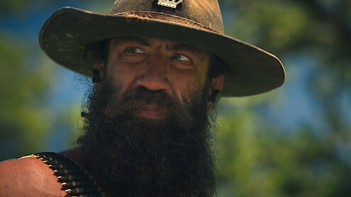 "Live King" Brian Johnson wearing a hat with a bullet belt over his shoulder.