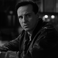 Black and white photo of Andrew Scott as Tom Ripley sitting at a bar in 'Ripley'