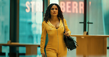 Salma Hayek as XX wearing a yellow jumpsuit and a black purse in Season 6 of Black Mirror..