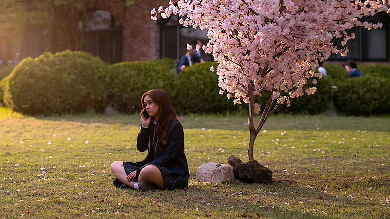 Anna Cathcart as Kitty Song Covey sits under a tree with pink blossoms in Season 2 of 'XO, Kitty' 