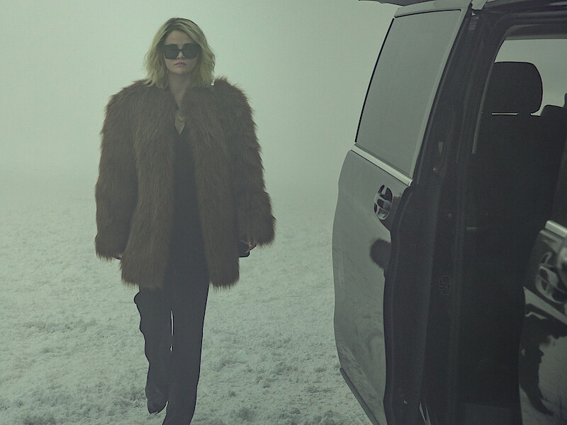 Jessi (Selena Gomez) wears a fur jacket and walks through the snow.