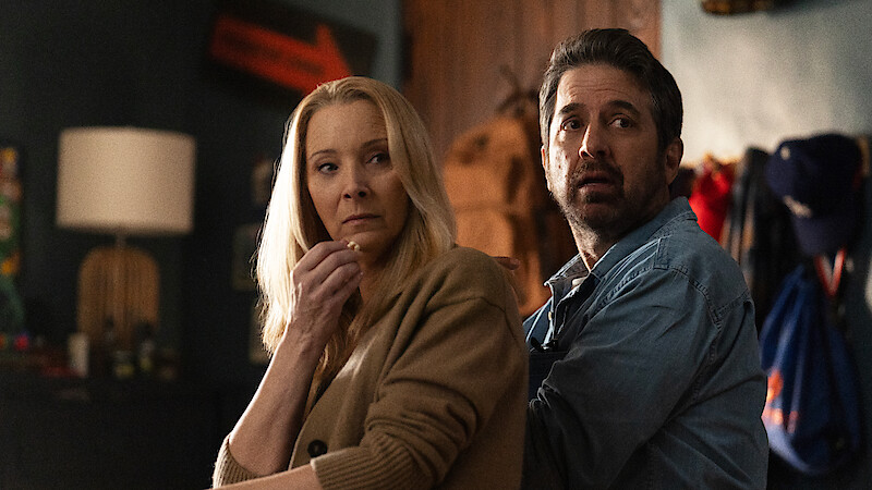 Lisa Kudrow and Ray Romano sit on a couch and look over their shoulders in Season 1 of 'No Good Deed.'