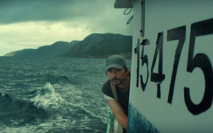 Josh Hartnett as Calvin Penney on fishing boat 15475 Josh Hartnett as Calvin Penney peering around a fishing boat marked 15475 in Netflix Below