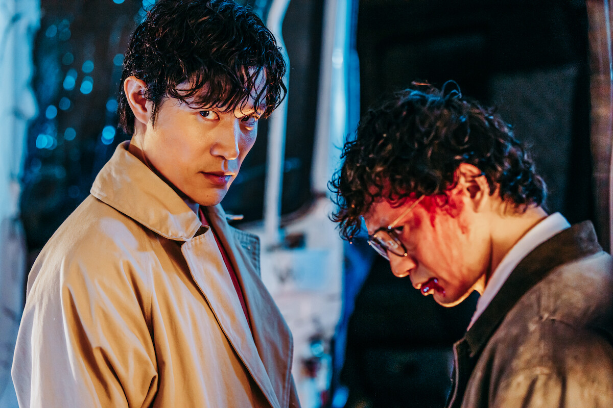 Ryohei Suzuki as Ryo Saeba looks to camera, and Masanobu Ando as Hideyuki Makimura looks down with a bloodied face in an image from the film ‘City Hunter.’