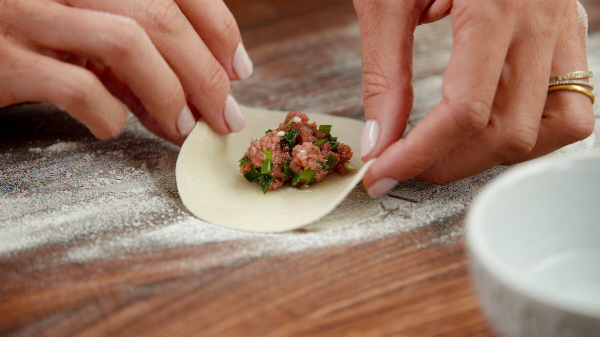 Potsticker filling being put into a dumpling wrapper.