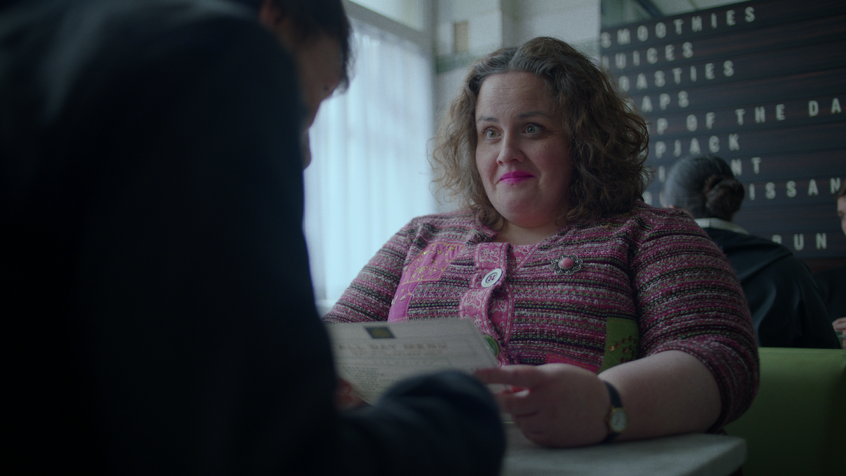 Jessica Gunning as Martha sits at a restaurant wearing a pink cardigan ad pink lipstick in ‘Baby Reindeer.’