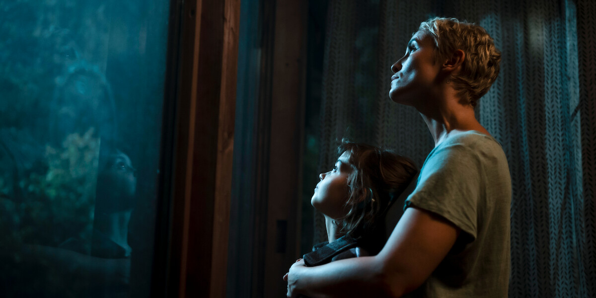 While staring out a window, Peri Baumeister as Paula embraces Yuna Bennett as Charlie in a still image from ‘The Signal.’