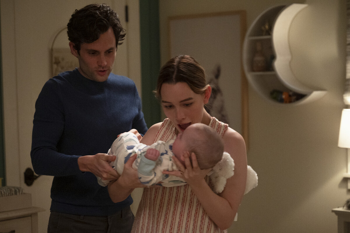 Penn Badgley's Joe Goldberg and Victoria Pedretti's Love craddling their infant son Henry.
