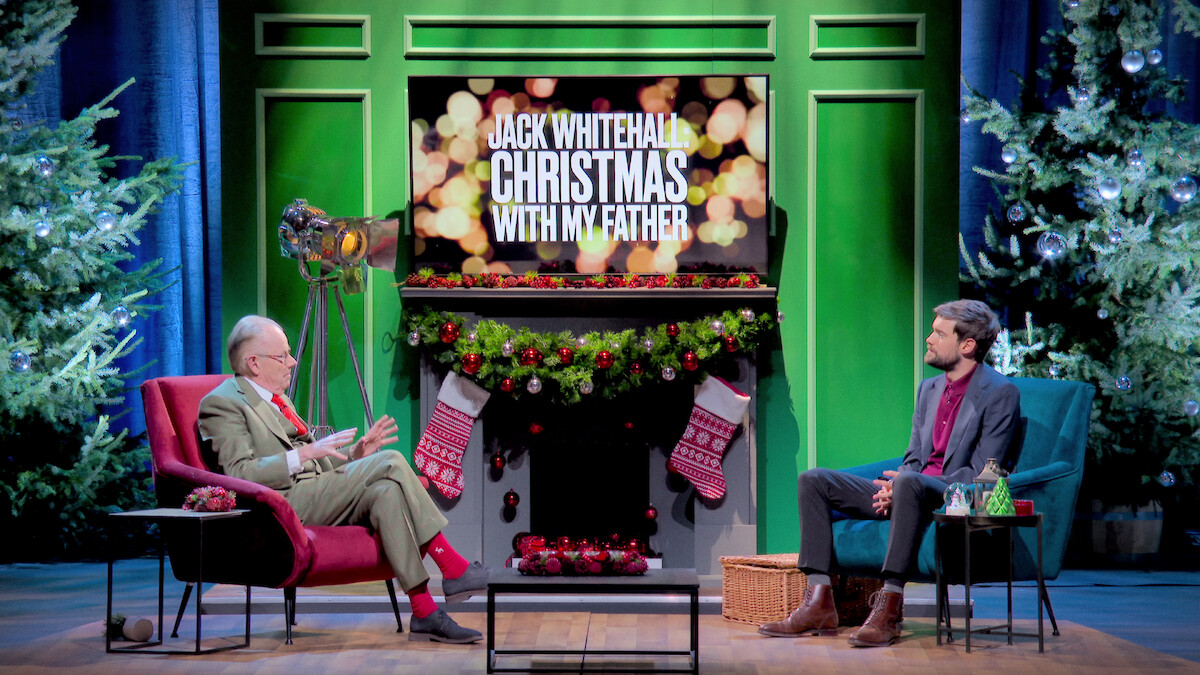 a father and son sit together on a holiday-decorated set.