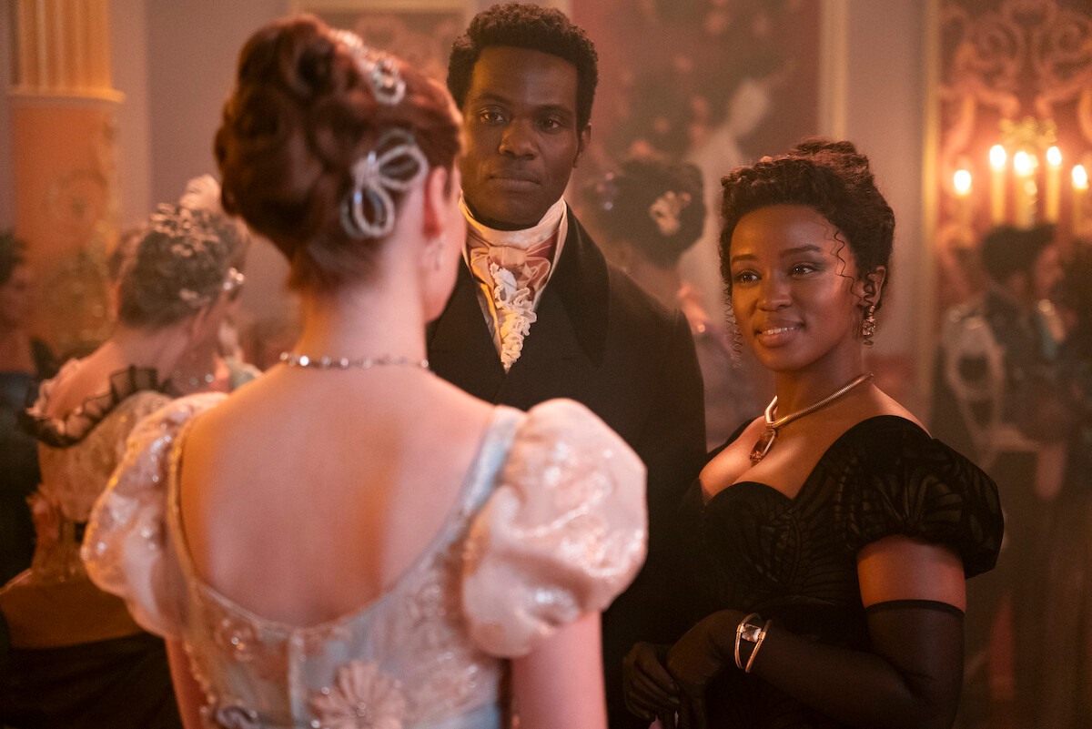 Hannah Dodd como Francesca Bridgerton, Victor Alli como John Stirling e Masali Baduza como Michaela conversam em um baile na temporada 3 de ‘Bridgerton’.