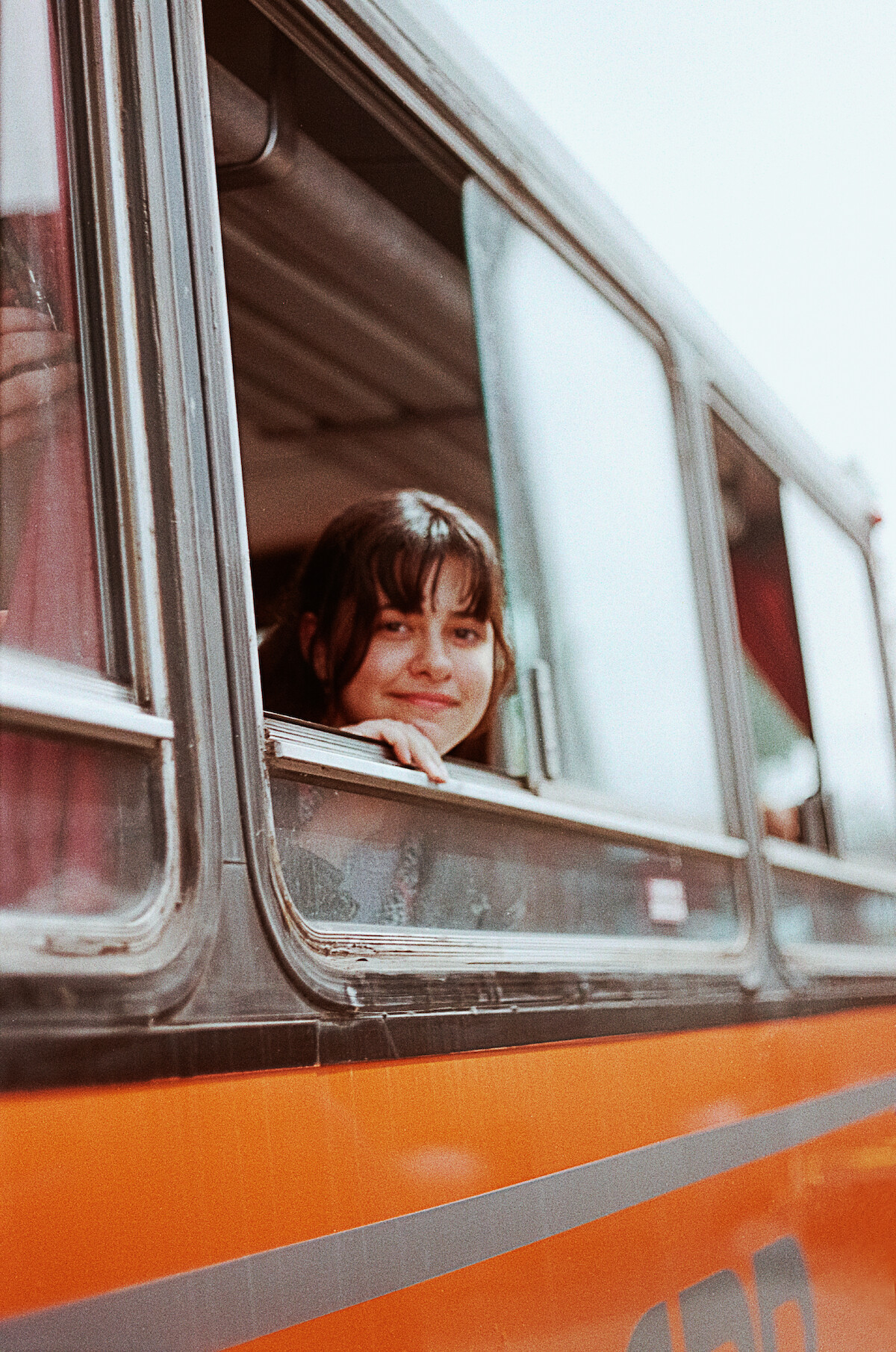 Grace Edwards peeks out of a bus window on set of Jay Kelly in Italy.