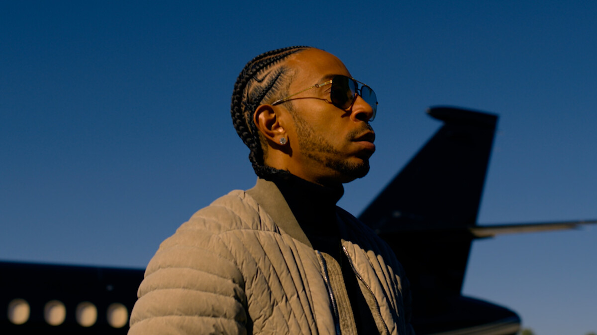 Ludacris wearing sunglasses standing in front of a jet.