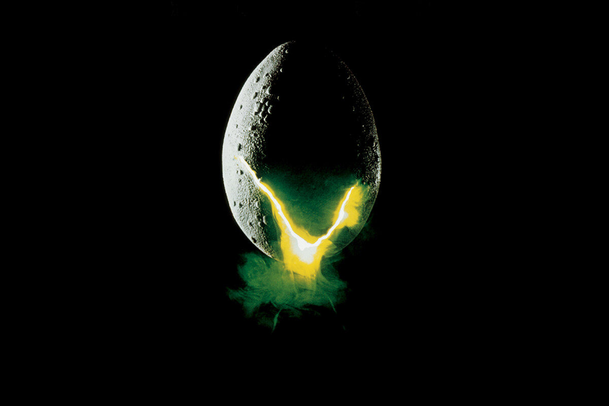 An egg-shaped object with a cracked surface emits a glowing yellow-green light and mist against a dark, black background.
