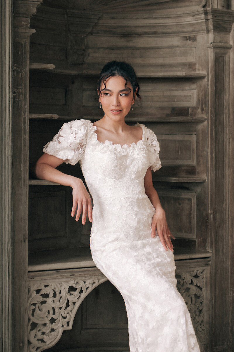 Woman in bridal dresses poses and looks off into the distance.