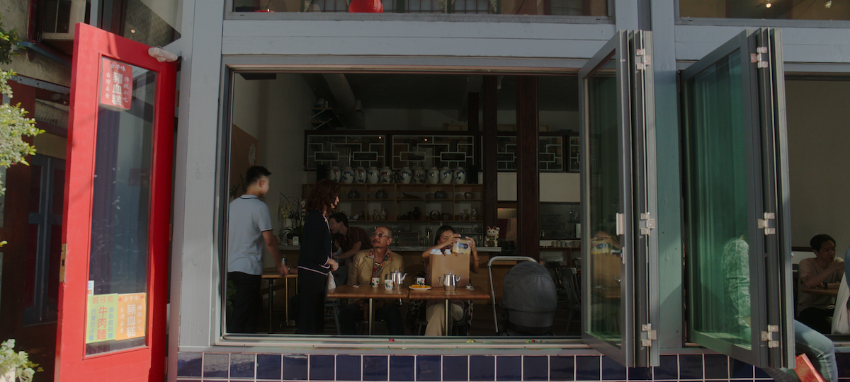 An exterior shot of a small restaurant with a red door and blue tiles in season 1 of ‘The Brothers Sun’