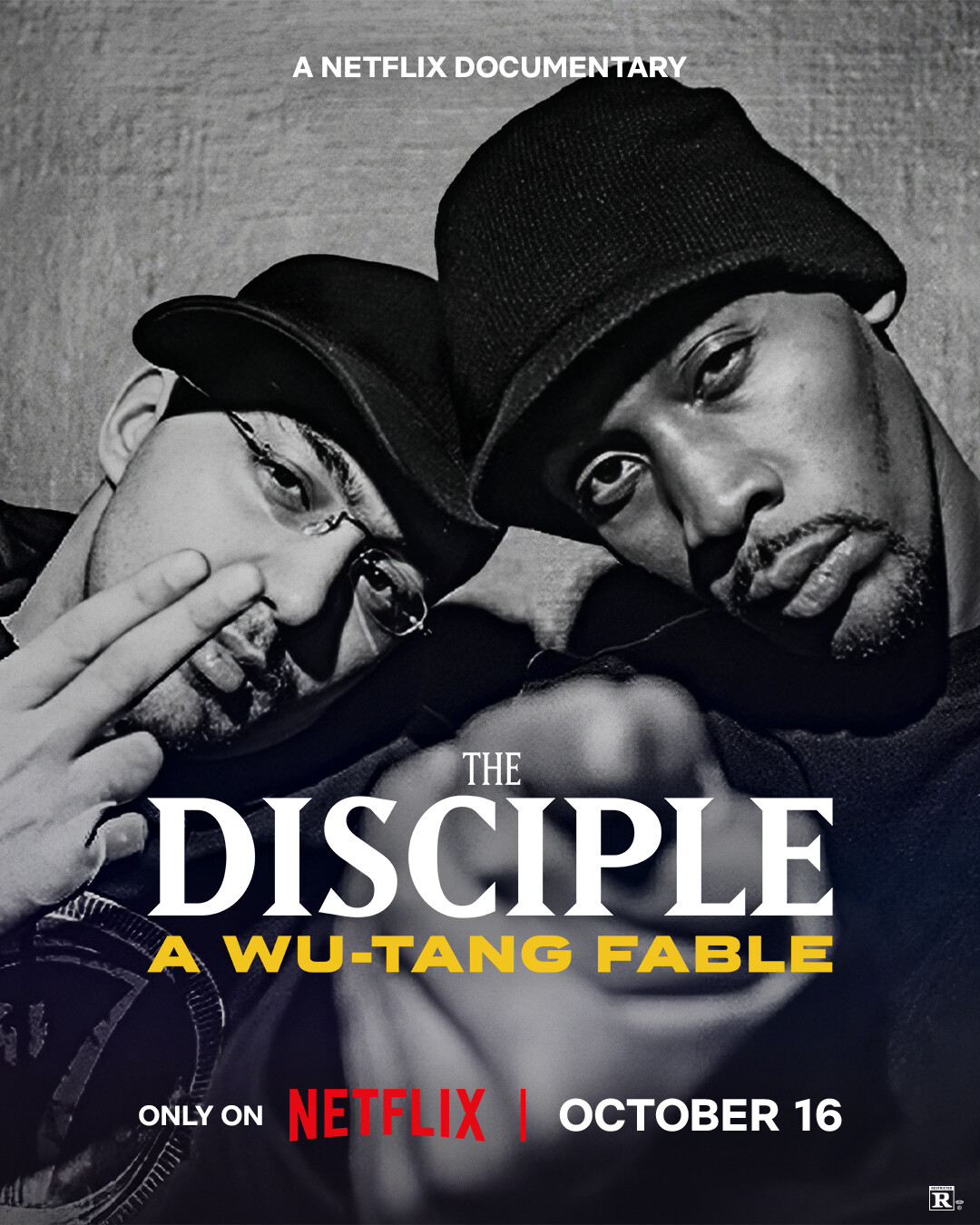 Two men in dark clothing and hats pose closely together, making hand gestures in a gritty urban setting. Promotional poster for “The Disciple: A Wu-Tang Fable,” a Netflix documentary premiering October 16.