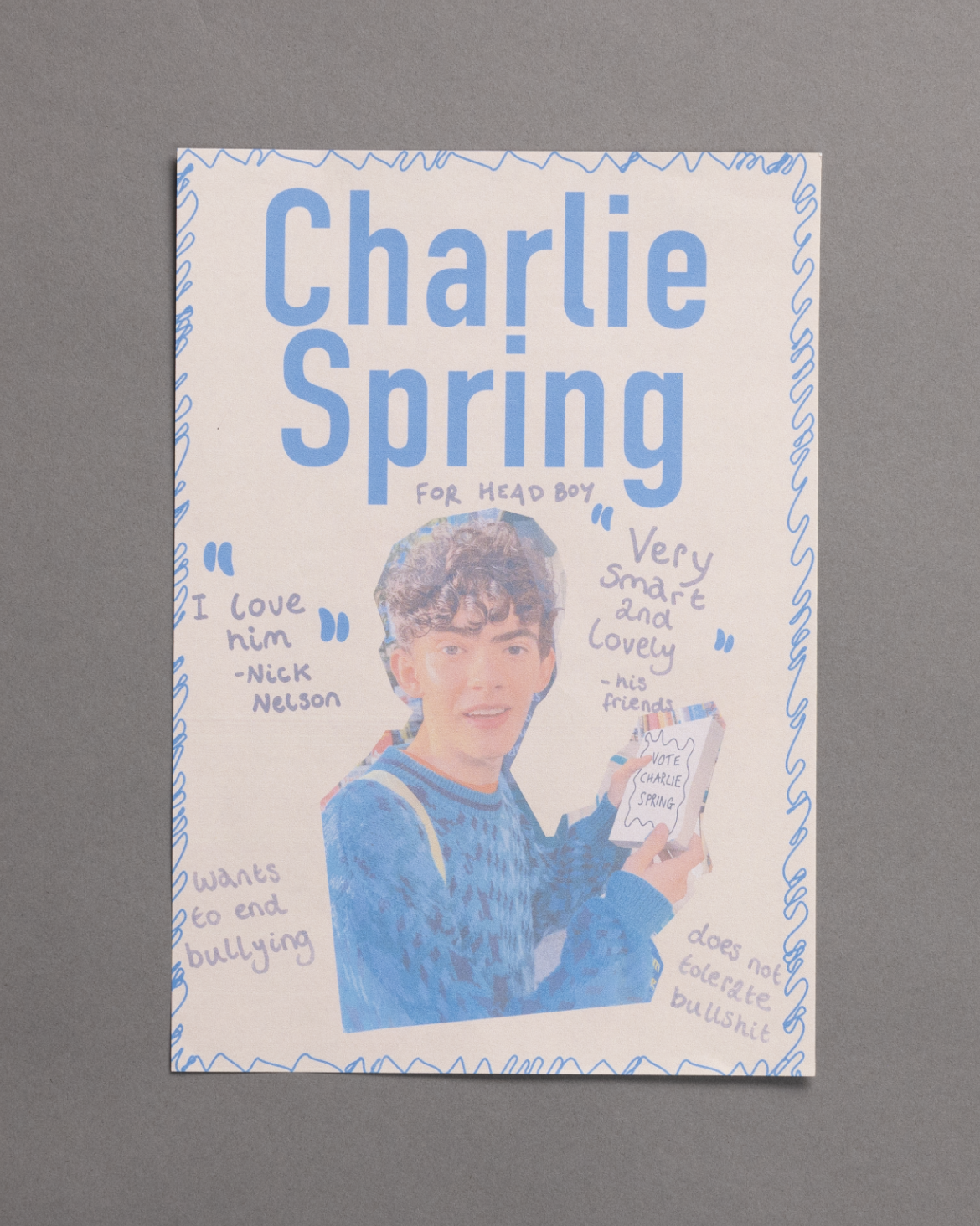 A campaign poster for Charlie Spring running for head boy, featuring a drawing of a boy in a blue sweater holding a clipboard, surrounded by positive quotes and doodles, against a gray background.