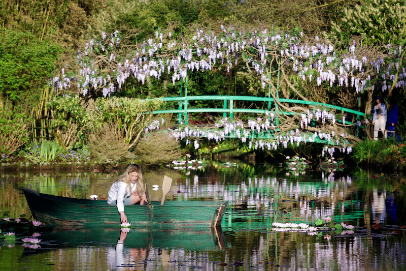 Camille Razat as Camille rows a boat in a lily pond in Season 4 of 'Emily in Paris'