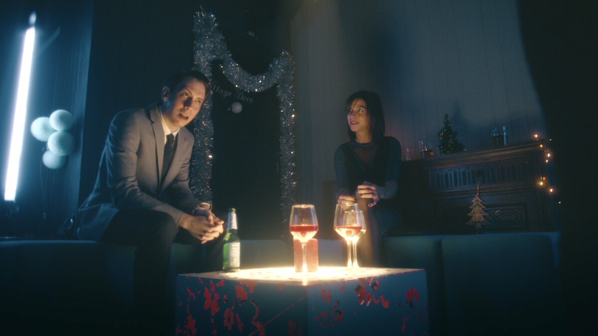 a man and woman in a room with drinks and Christmas decorations.