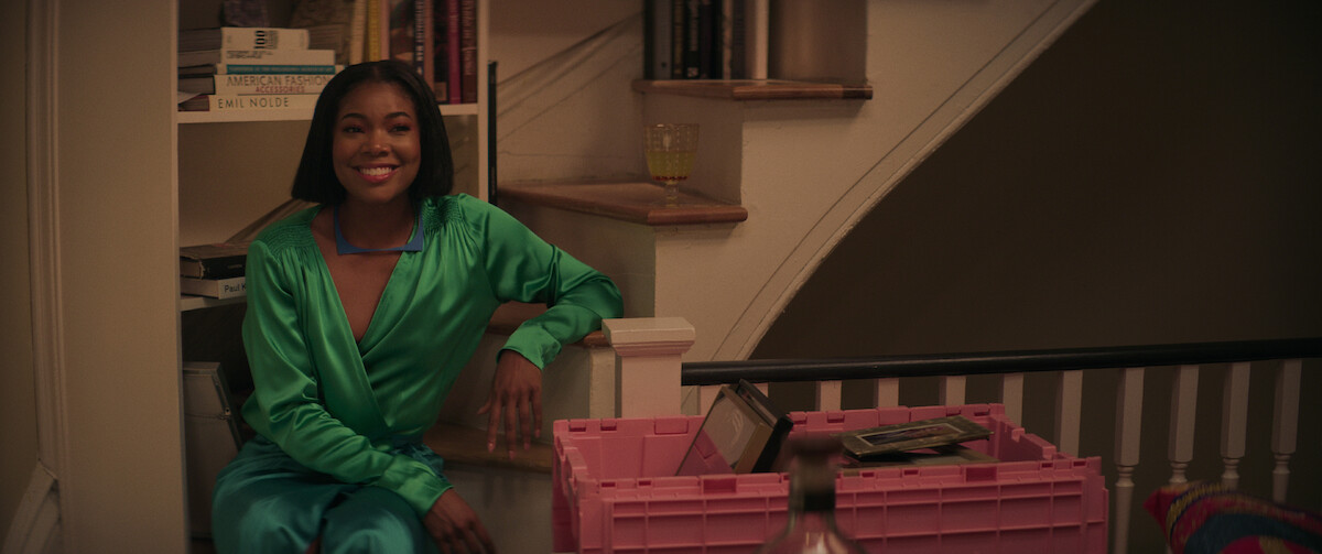 Gabrielle Union sits on stairs wearing a green silk dress in a still from ‘The Perfect Find.’