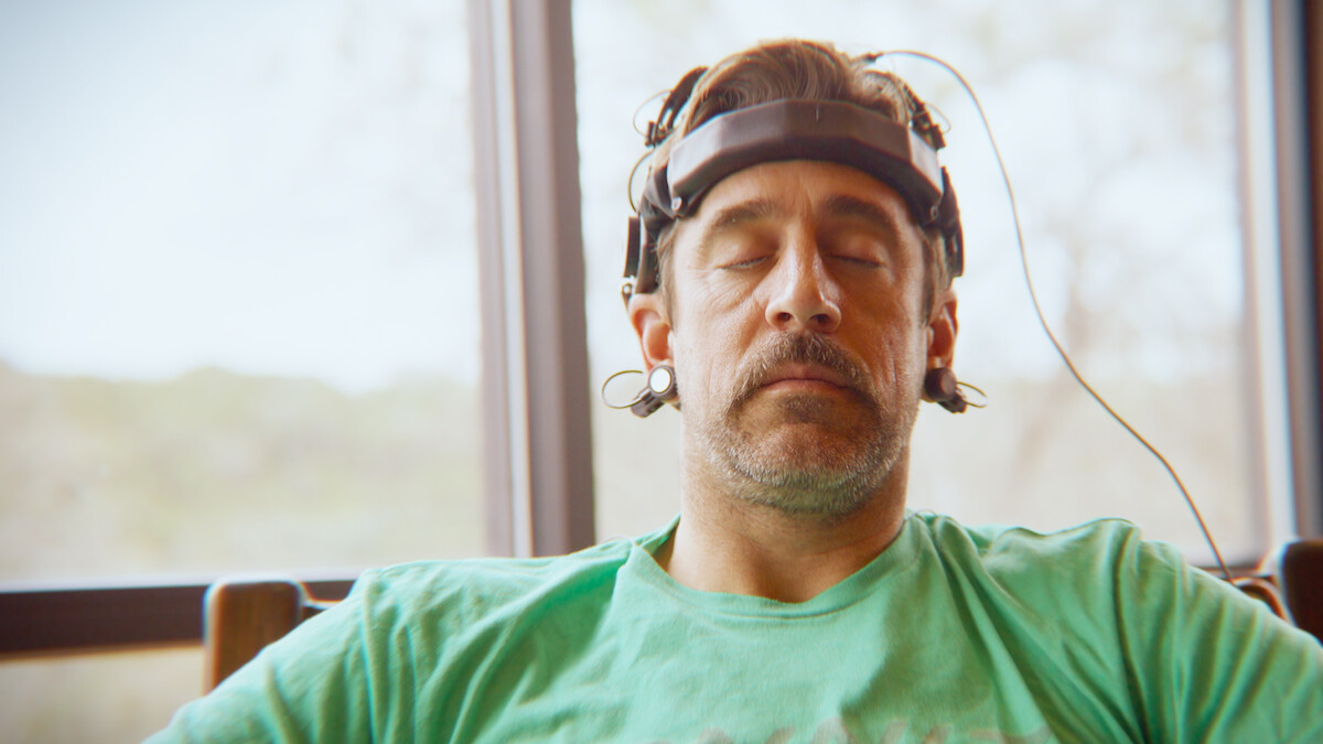 Aaron Rodgers sitting in a chair with his eyes closed.