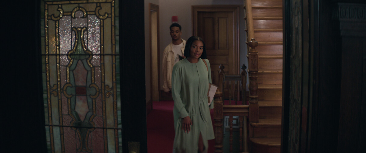 Gabrielle Union walks through a brownstone door wearing a green mint dress in front of Keith Powers in a still from ‘The Perfect Find.’