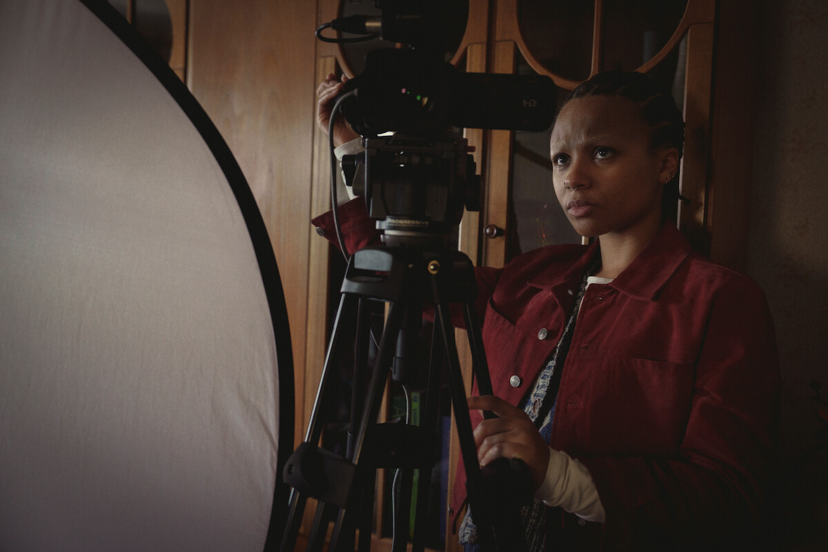 Myha’la Herrold as Pia in in Black Mirror Season 6 standing with camera equipment. 