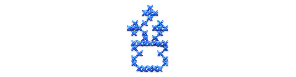 Blue cross stitched vase of flowers.