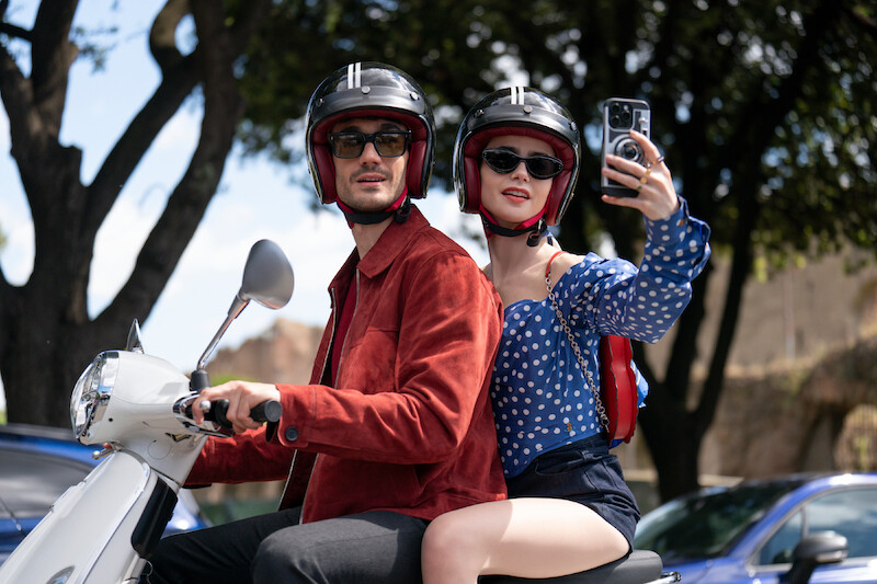 Lily Collins as Emily and Eugenio Franceschini as Marcello ride a scooter together in Season 4 of 'Emily in Paris'
