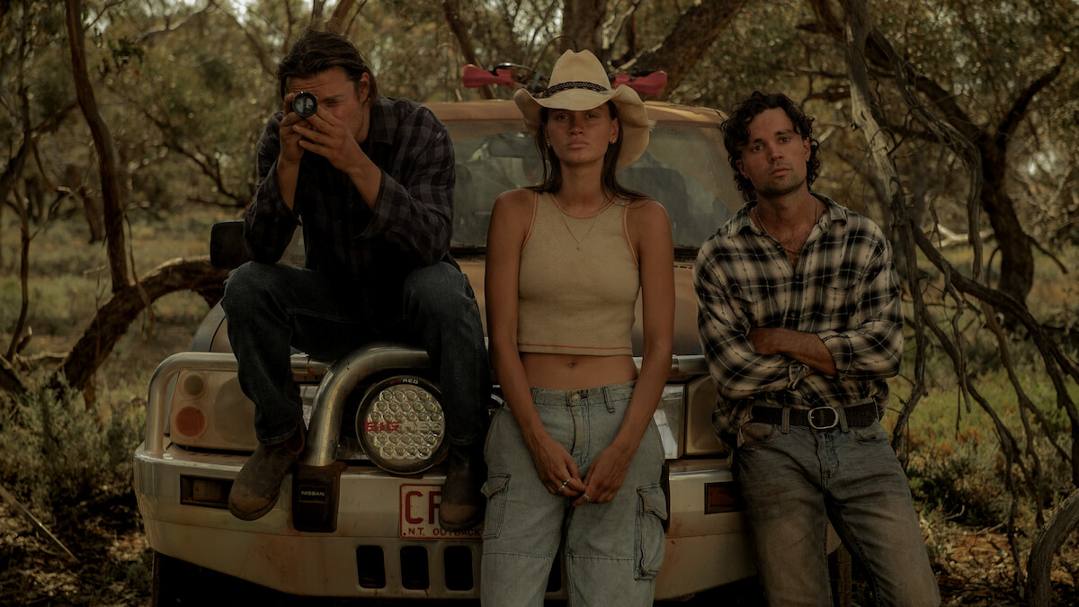 Kylah Day as Sharnie Kennedy, Sam Corlett as Marshall Lawson, and Sam Delich as Rich Petrakis lean on the hood of a car in Season 1 of ‘Territory’