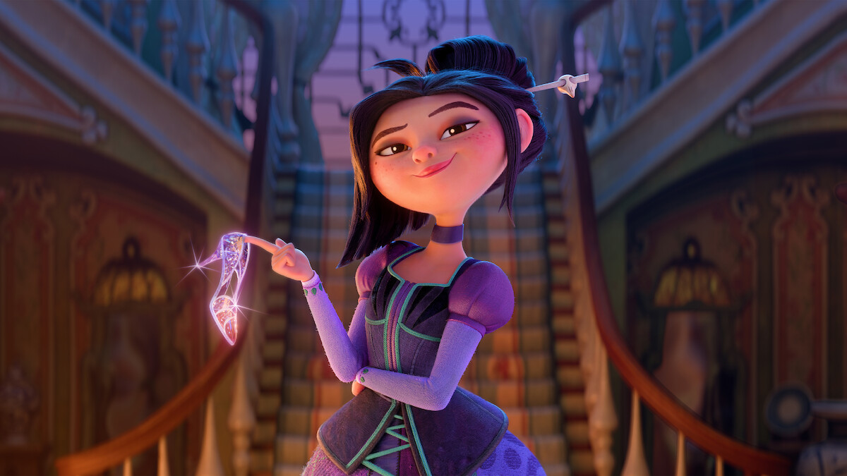 Animated girl with dark hair in a purple dress stands confidently holding a sparkling magical staff, set in a grand, ornate mansion with twin staircases and warm ambient lighting in the background.