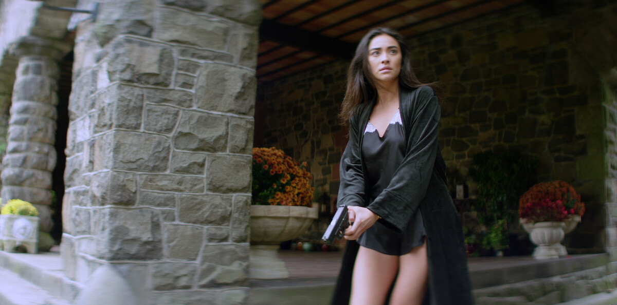 Peach (Shay Mitchell) at her Connecticut mansion, wearing a nightgown and holding a gun