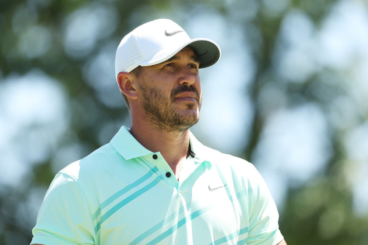 Golfer Brooks Koepka in a seafoam green Nike polo watching a shot.