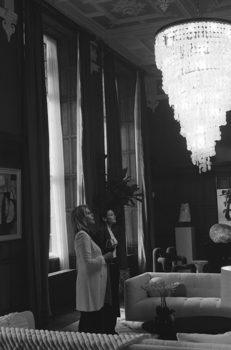 Black-and-white image of Joanna Lumley as Judith Baker and Michelle Keegan as Michelle Stern looking at a chandelier in Season 1 of 'Fool Me Once' 