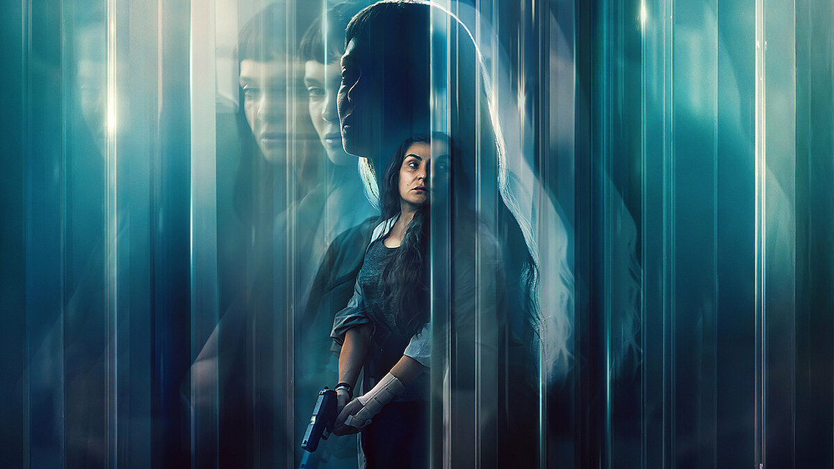 A woman holding a gun stands in a dark, mysterious environment with blue tones and blurred, ghostly reflections of herself and another woman, creating a suspenseful and intense atmosphere.
