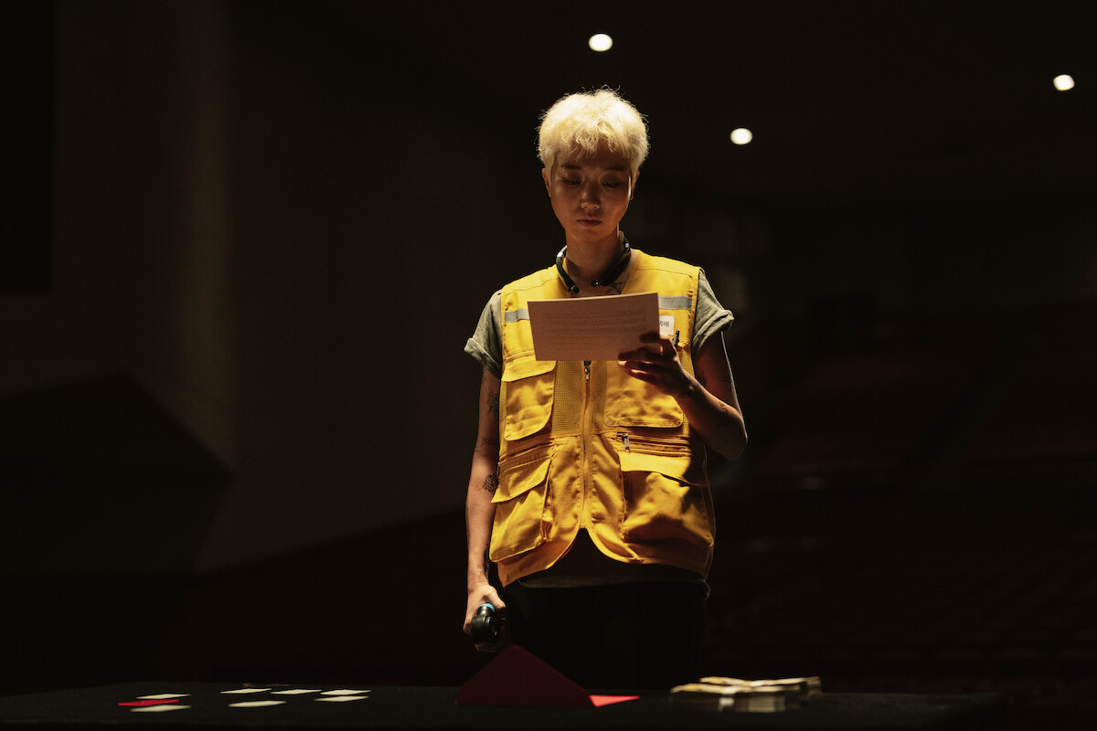 Lee Zoo-young as Second Floor reads a piece of paper in ‘The 8 Show.’