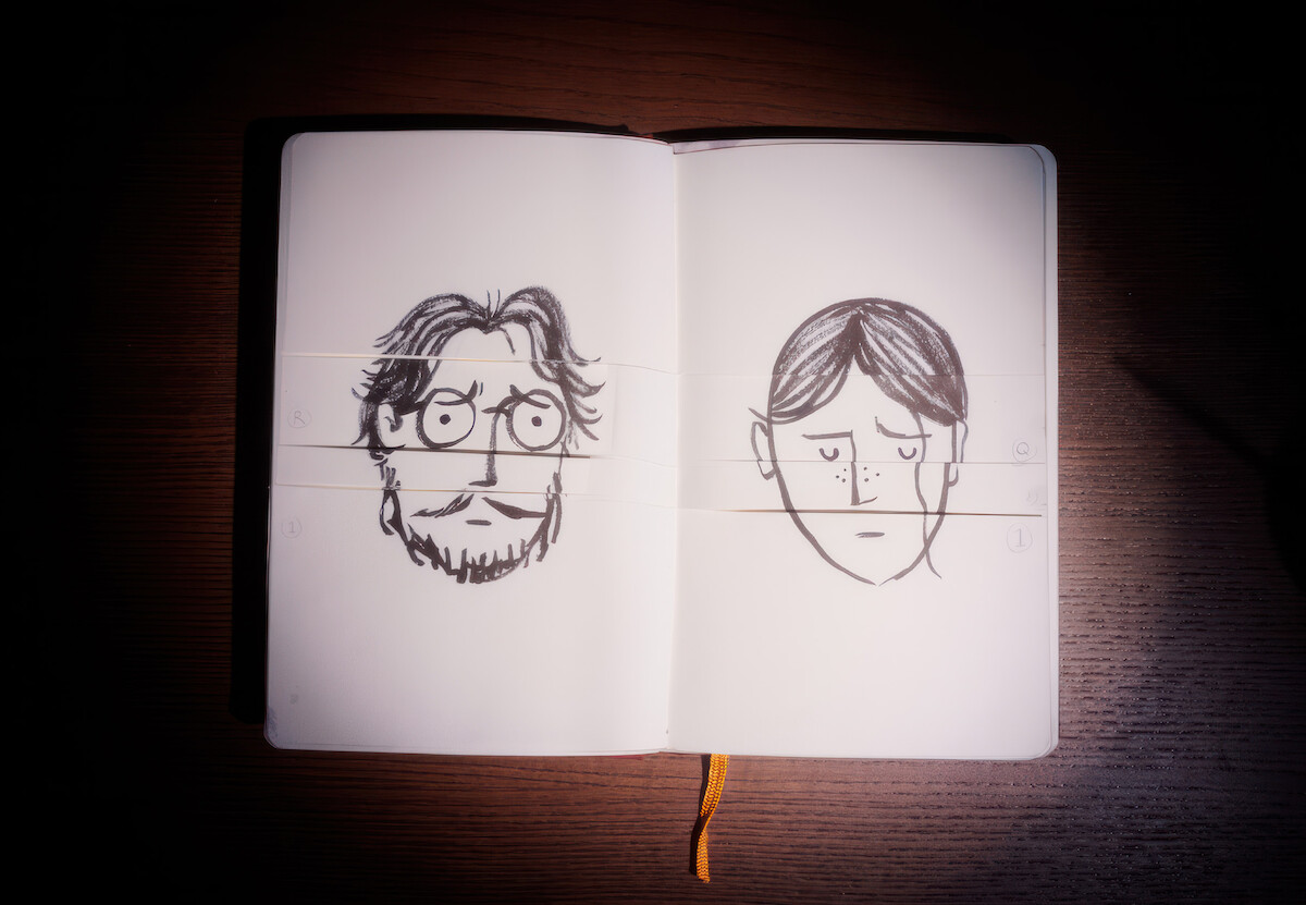 Um caderno de desenhos está aberto e exibe dois desenhos: os rostos tristes de um homem e uma mulher, um em cada página