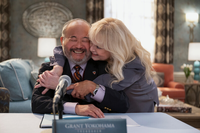 Clyde Kusatsu as Grant and Sally Struthers as Virginia embrace each other smiling in Season 1 of 'A Man on the Inside'