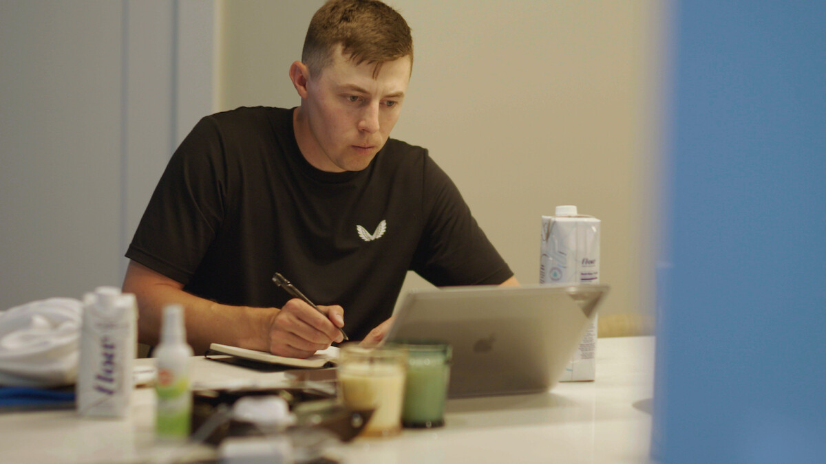 Golfer Matt Fitzpatrick sits at a kitchen table in front of an iPad, tabulating his golf statistics.
