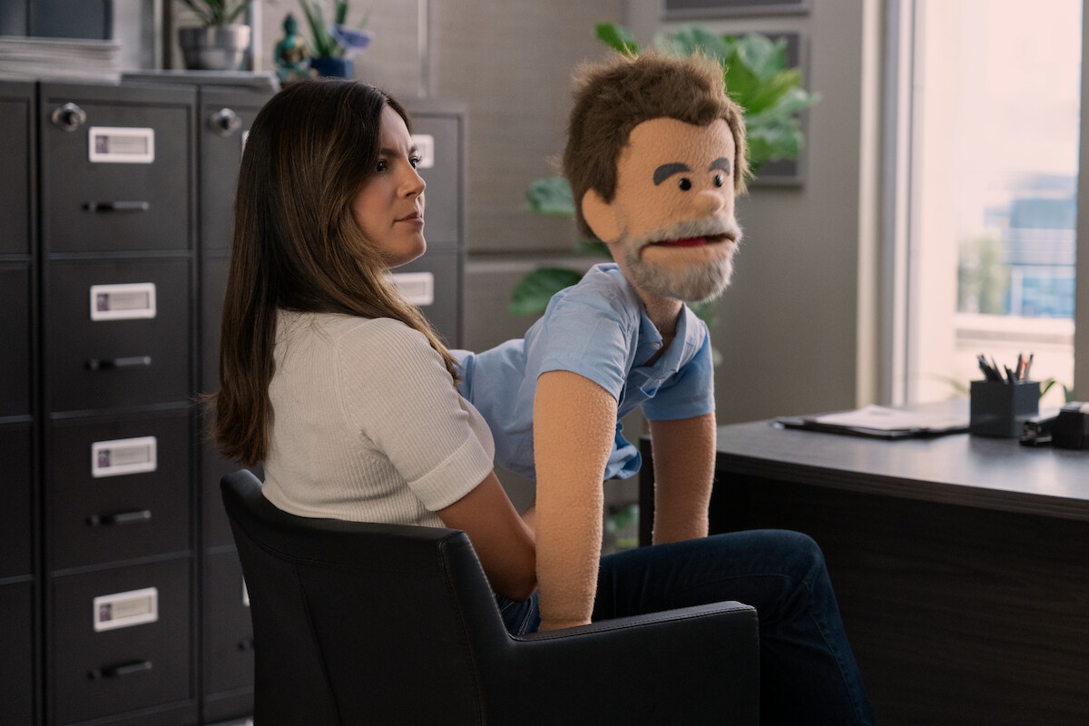 Monica Barbaro as Emma Brunner holding a puppet in FUBAR Season 1.