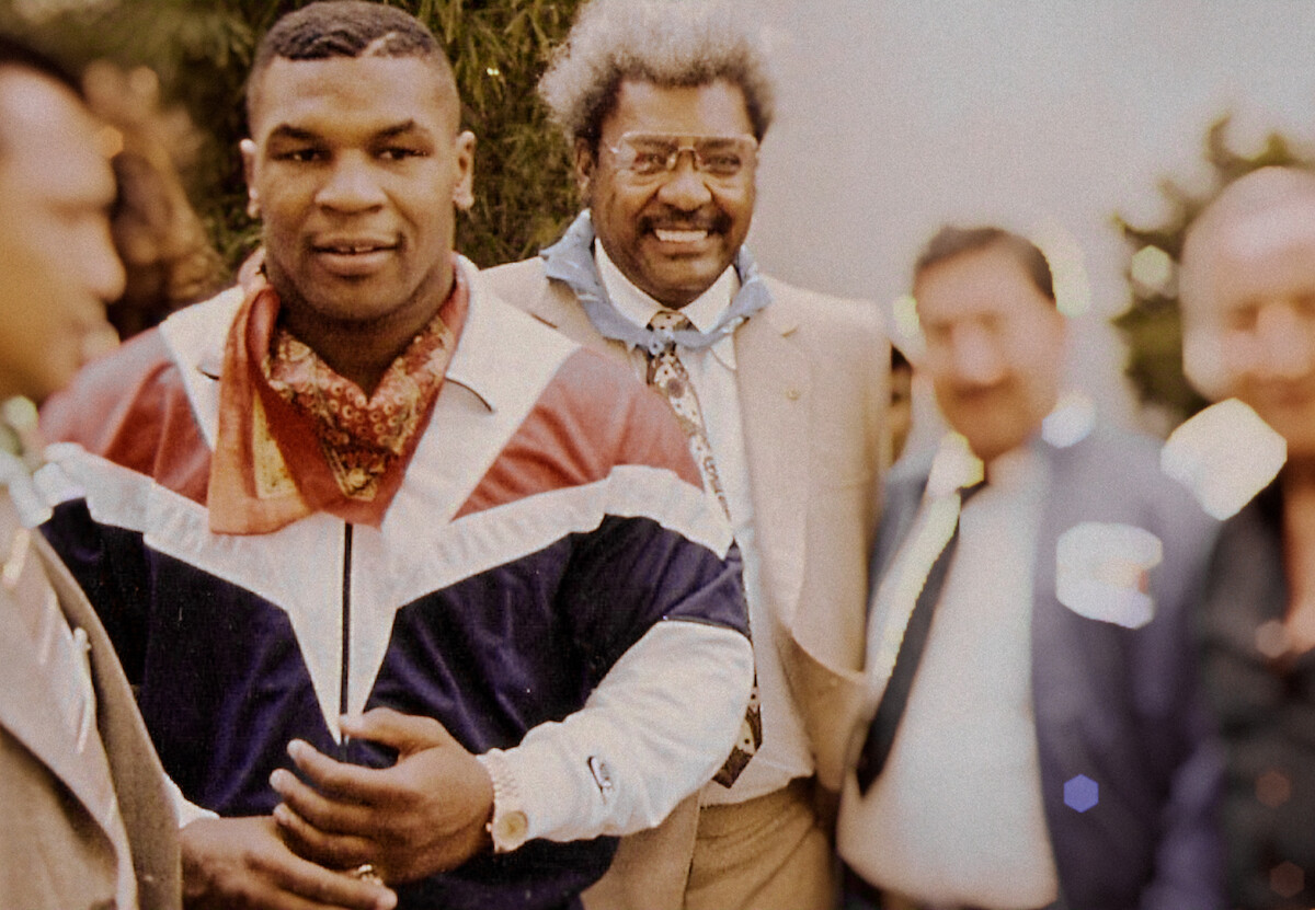 Uma foto antiga mostra Mike Tyson jovem, vestindo casaco branco, vermelho e azul e com cabelos curtos