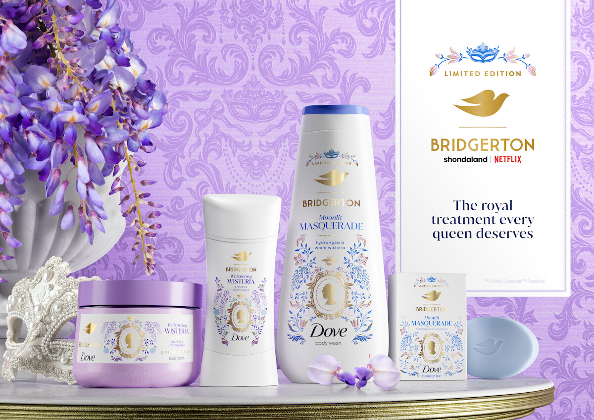 Dove x Bridgerton limited edition bath products on a gold tray with floral decor and a white mask, set against an ornate purple backdrop; includes body wash, deodorant, and body cream; elegant and regal atmosphere.