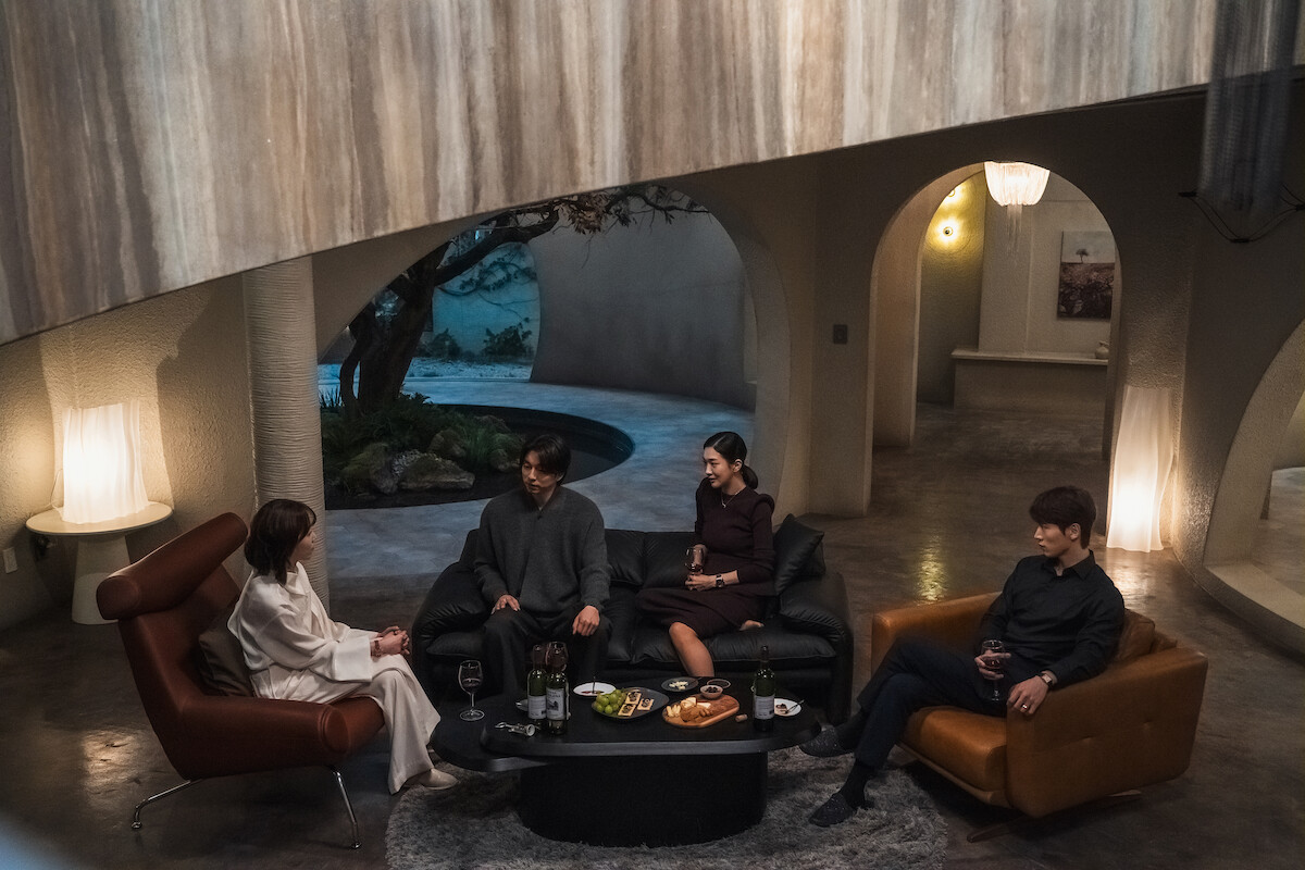 Seo Hyun-jin as Noh In-ji, Gong Yoo as Han Jeong-won, Jung Yun-ha as Lee Seo-yeon, and Jo I-geun as Yoon Ji-o sit together in a living room upon black and brown leather furniture in an image from the series ‘The Trunk.’