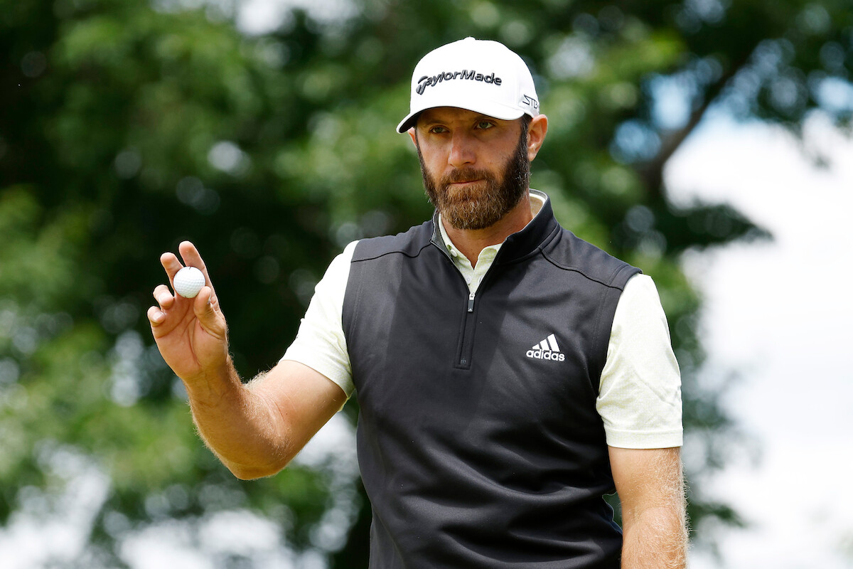 Golfer Dustin Johnson holds up a golf ball during an event.
