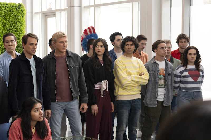 The cast of Season 6, Part 2 of 'Cobra Kai' gathers together with serious expressions. 